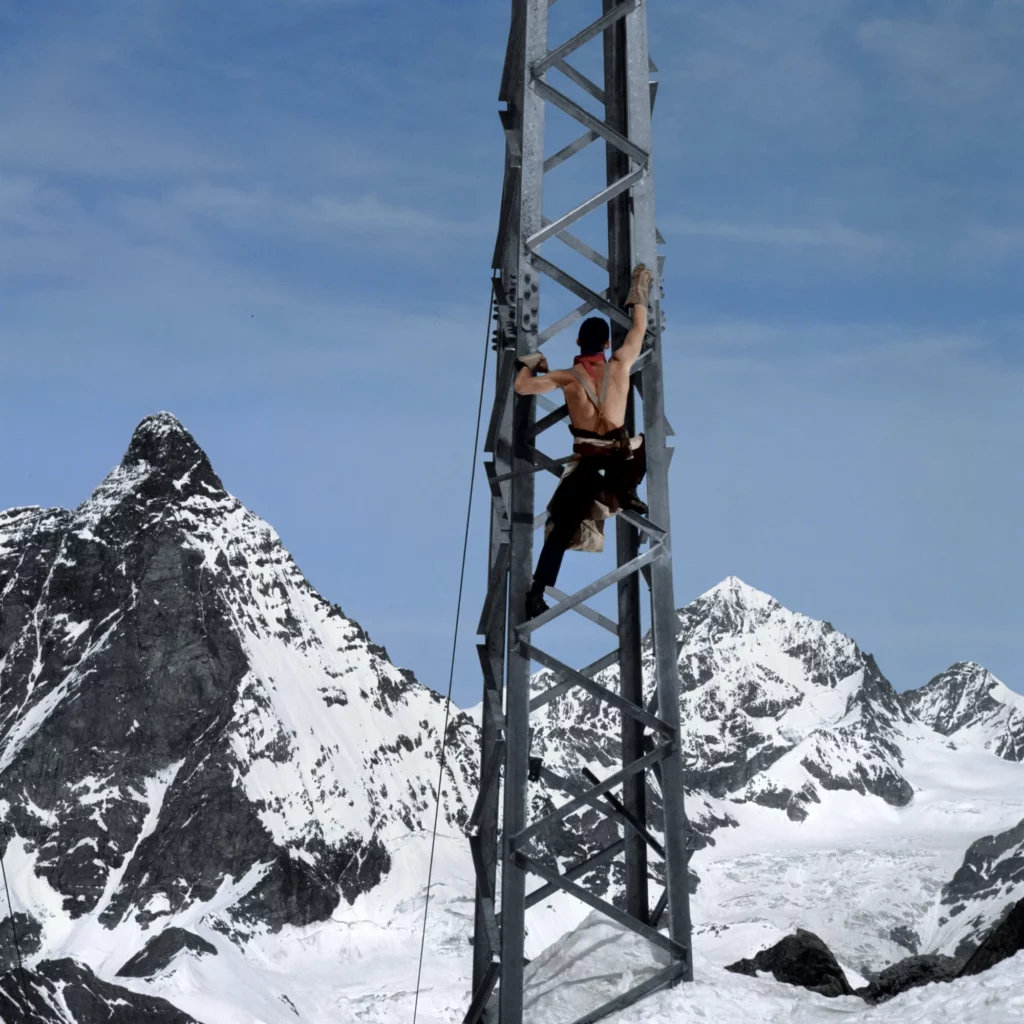 Shirtless man on a metal structure in the snowy mountains